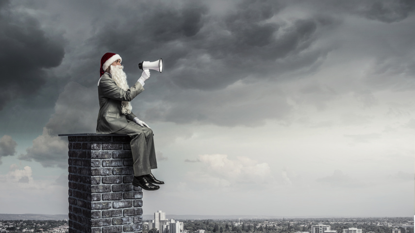 Businessman in Santa hat on house roof shouting in megaphone