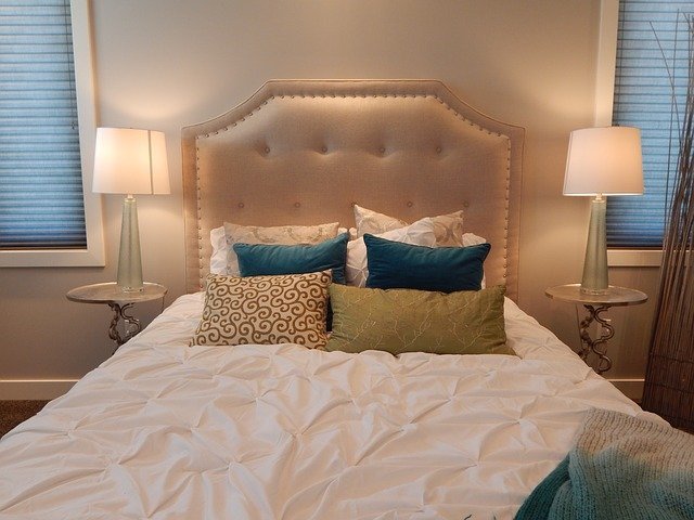 Łoże w sypialni z pikowanym zagłówkiem i stosem eleganckich poduszek