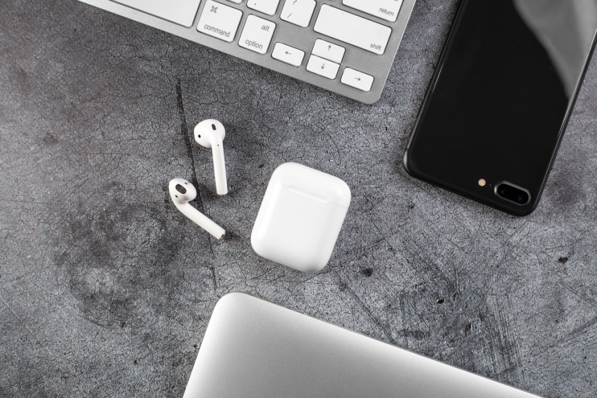 Apple Earpods leżą na szaryb blacie biurka międzt innymi sprzętami komputerowymi