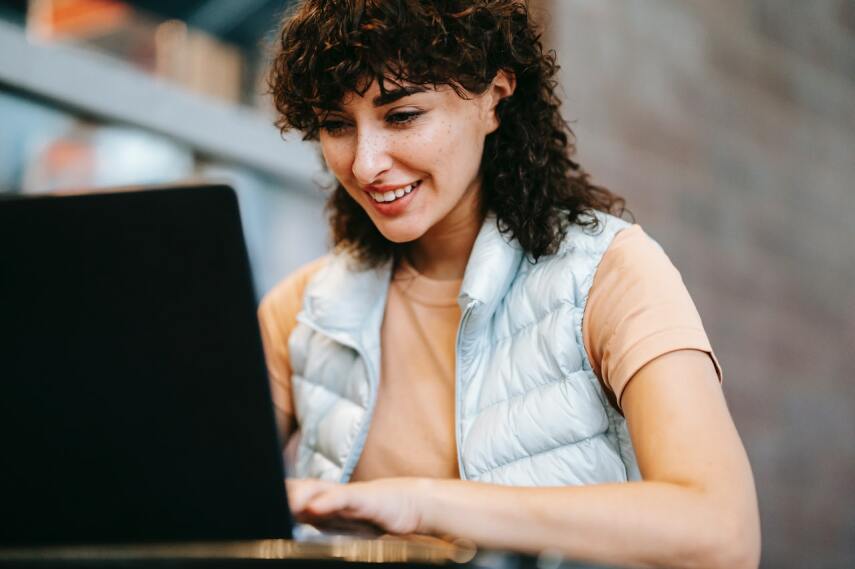 Kobieta o kręconych włosach spogląda w monitor laptopa