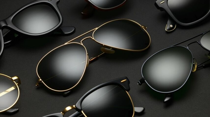 Ustawione w rzędach, na czarnym tle okulary przeciwsłoneczne w czarnych lub złotych, metalowych oprawkach