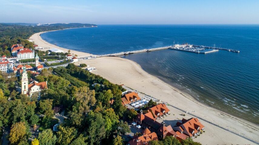 Z lotu ptaka widok na najpiękniejsze polskie plaże - plaża w Sopocie z molem, lasem i domami o czerwonych dachach
