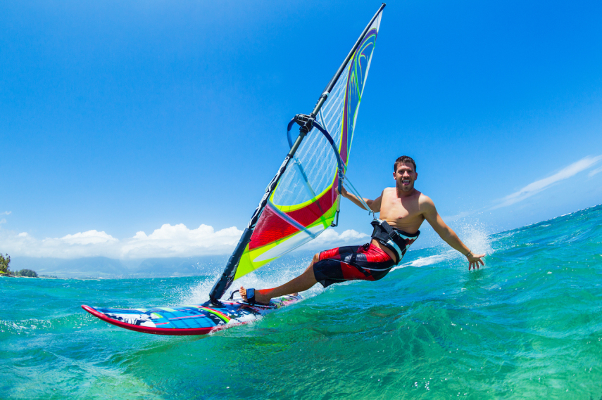 Mężczyzna w półpiance na desce windsurfingowej sfilmowany kamerą sportową