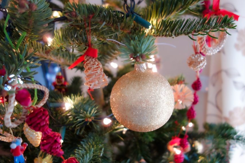 Gałązka świątecznej choinki z brokatową białą bombką i innymi ozdobami