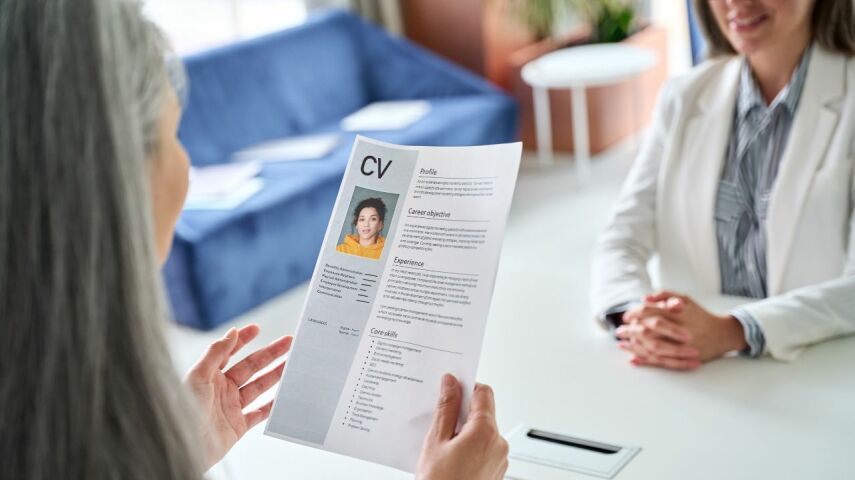 Na rozmowie kwalifikacyjnej kobieta prezentuje hr cv z idealnym zdjęciem do cv