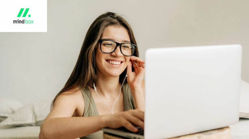 Kobieta w okularach rozmawia przez telefon pracując na laptopie jako freelancer w branży IT