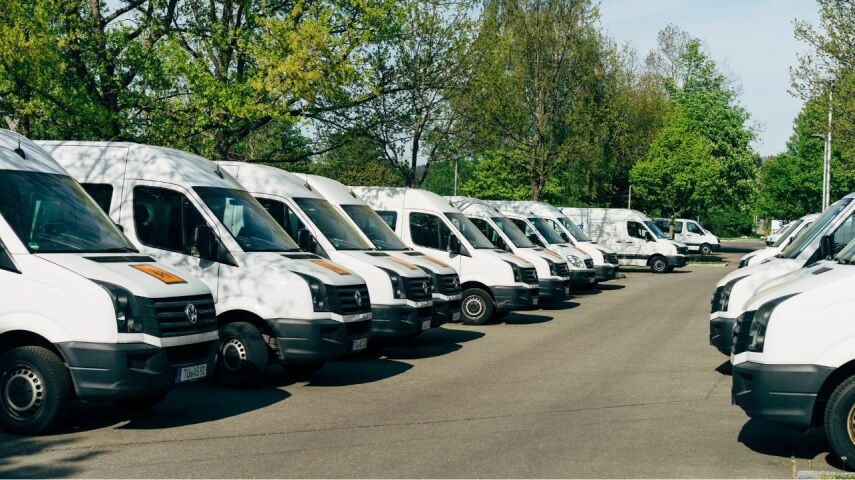 Flota białych samochodów dostawczych w dwóch rzędach na parkingu