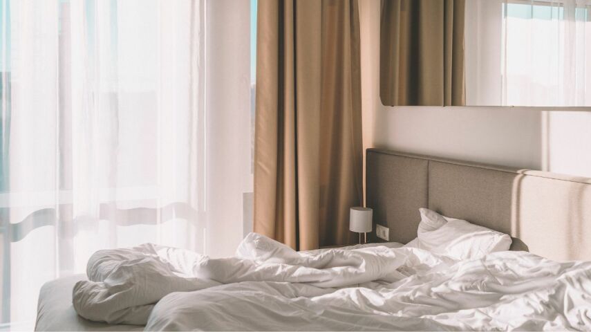 Elegancka sypialnia z pięknymi jasnymi firanami i beżowymi zasłonami w oknach