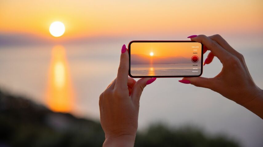 iPhne w dłoniach w trakcie robienia zdjęcia zachodu słońca